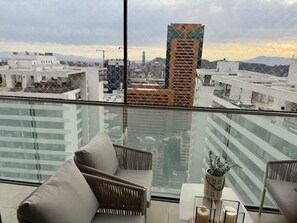 A balcony with a city view, a sofa, and a potted plant. - Modern apt with king bed, sofa bed, washer/dryer, terrace. Near Parque Arauco. (Las Condes)