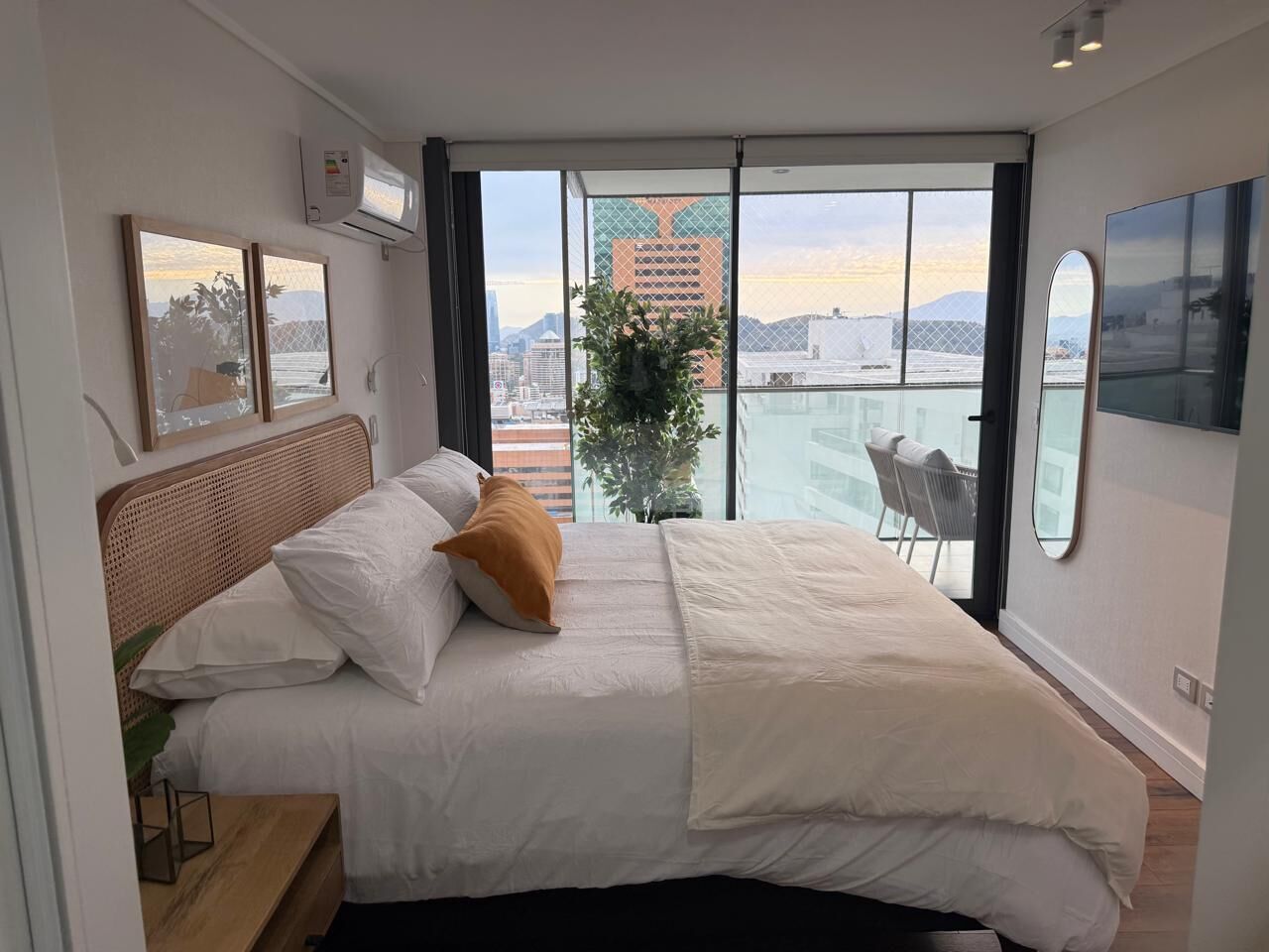 Une chambre moderne avec un grand lit, une vue sur la ville et un balcon.