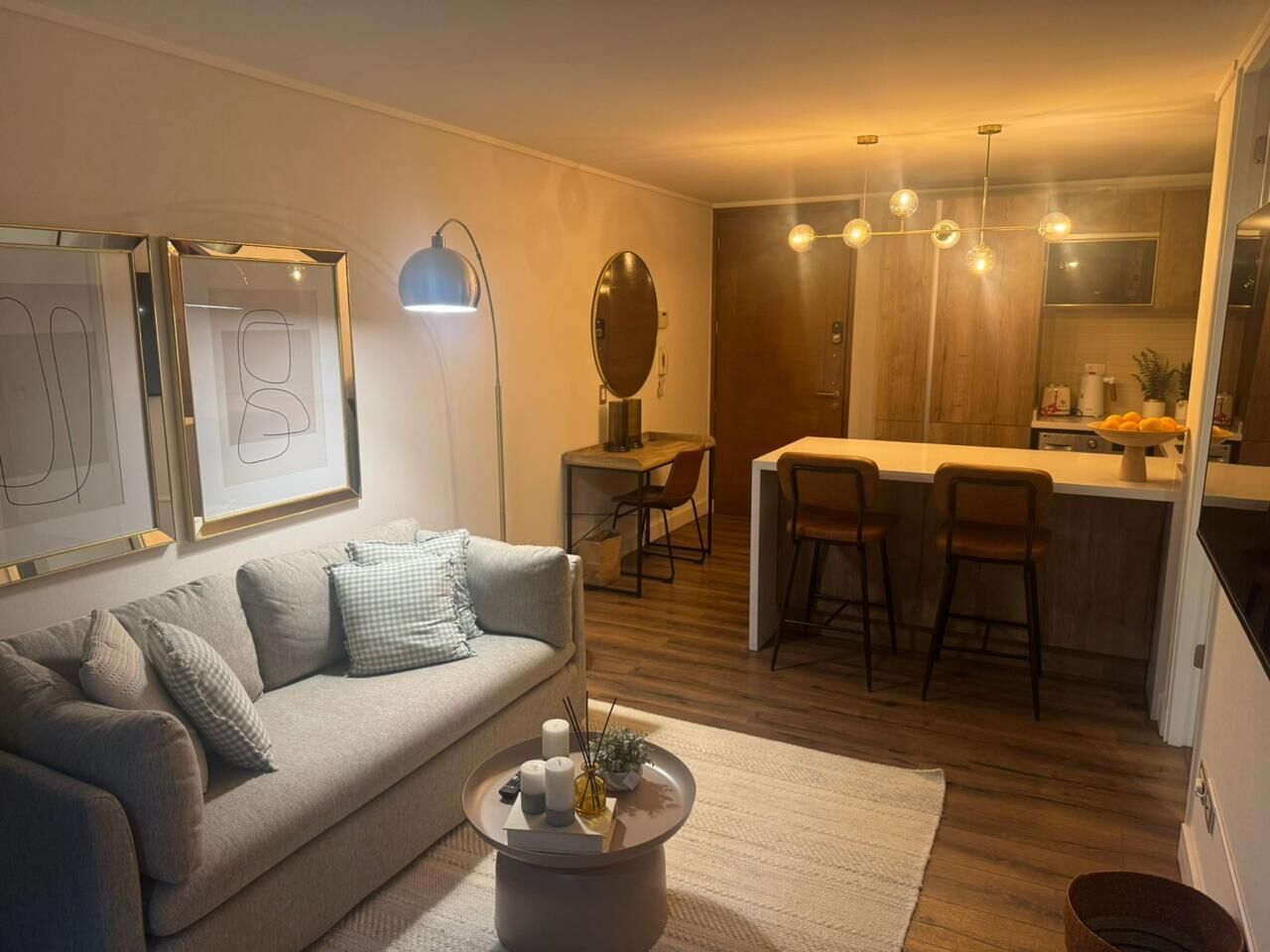 Ein modernes Wohnzimmer mit einer Couch, einem Couchtisch und Kunstwerken. Im Hintergrund ist ein Essbereich mit Tisch und Stühlen zu sehen.