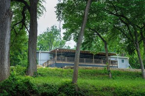 A cabin with a deck, surrounded by trees and greenery. - 4 bed, 2 bath home on the Brazos River and less than 4 miles from Lake Whitney. (Clifton)