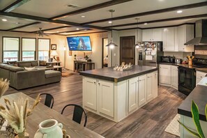 A spacious living area with a large island, a kitchen with modern appliances, and a dining area with a table and chairs. - 4 bed, 2 bath home on the Brazos River and less than 4 miles from Lake Whitney. (Clifton)