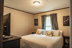 A hotel room with a bed, a desk, a mirror, and two wall-mounted picture frames. - 4 bed, 2 bath home on the Brazos River and less than 4 miles from Lake Whitney. (Clifton)
