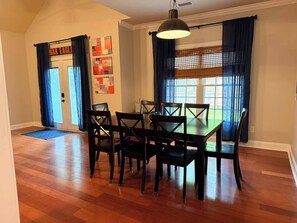 Un comedor con una mesa y sillas, una lámpara colgante y una puerta con un letrero.