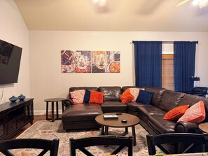 Een woonkamer met een leren bank, een salontafel en een tv op een meubel.