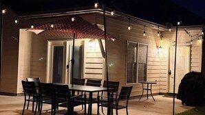 En udendørs patio med et bord og stole, et overdækket siddeområde og en grill.