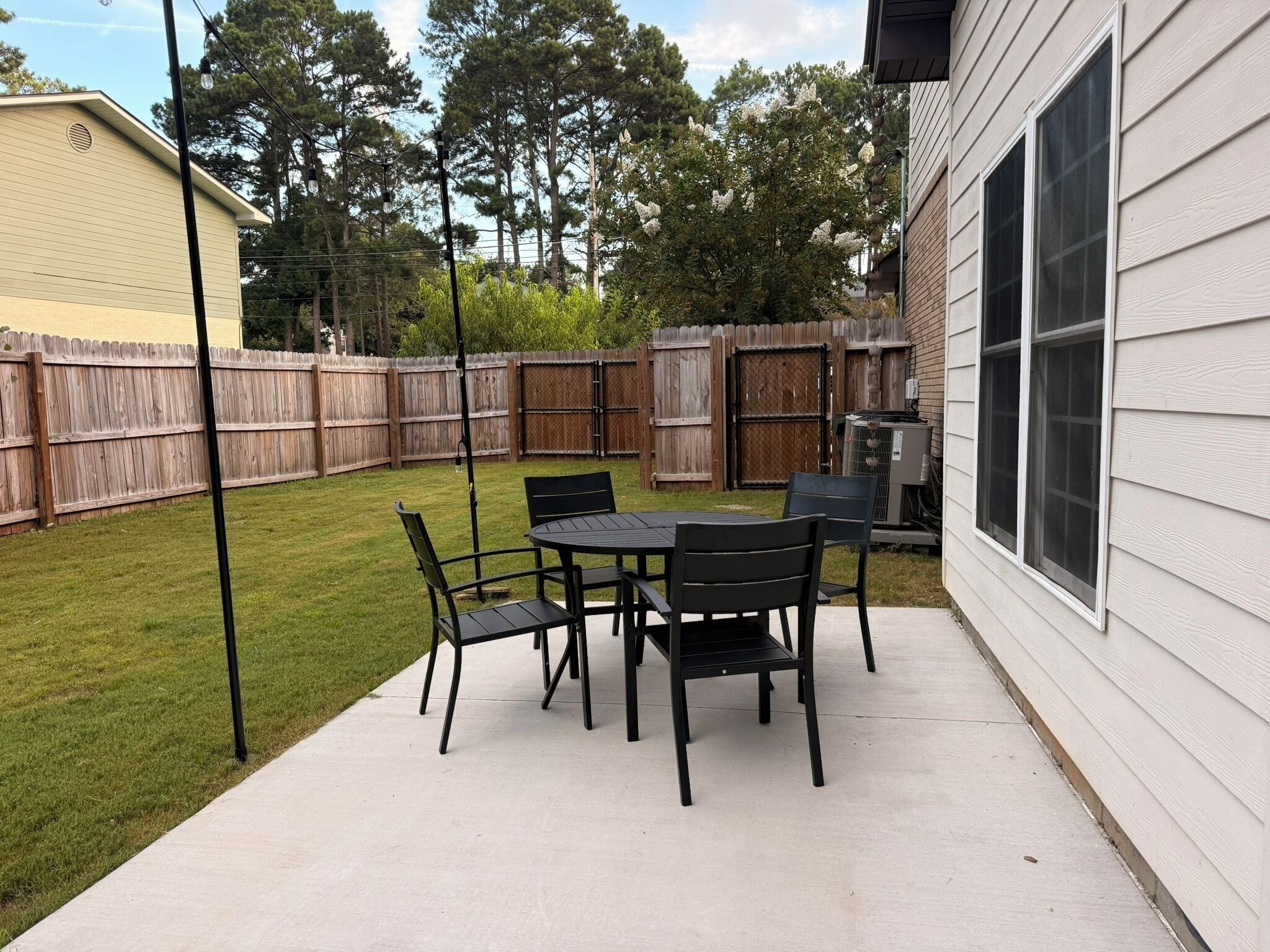 Eine Terrasse mit Tisch und Stühlen, ein Holzzaun und ein Gebäude im Hintergrund.