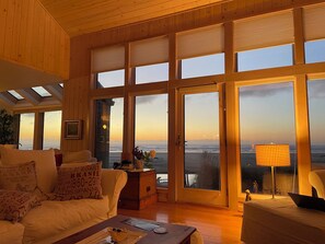 Ein geräumiges Wohnzimmer mit einem großen Schiebeglasfenster, das auf einen Balkon mit Meerblick führt.