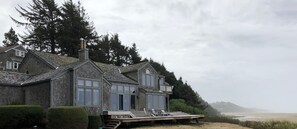 Ein Küstenhaus mit einer Terrasse, großen Fenstern und Blick auf den Strand.