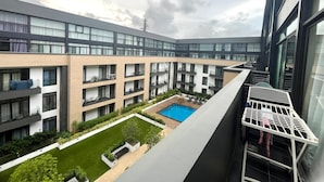 A modern multi-story residential building with a central courtyard featuring a swimming pool and green spaces. - Studio Apartment  (Accra)
