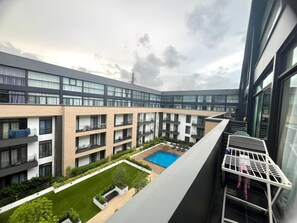 A modern multi-story residential building with a central courtyard featuring a swimming pool and green spaces. - Studio Apartment  (Accra)
