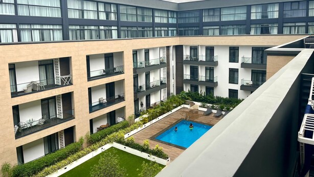 A multi-story building with balconies, a swimming pool, and a rooftop terrace. - Studio Apartment  (Accra)