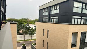 A modern building with a flat roof, multiple windows, and a gated entrance. - Studio Apartment  (Accra)