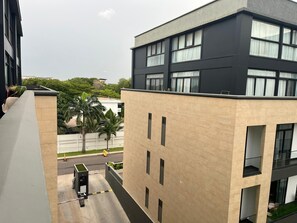 A modern building with a flat roof, multiple windows, and a gated entrance. - Studio Apartment  (Accra)