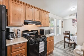 A compact kitchen with wooden cabinets, a stove, a microwave, and a coffee maker. - West Sedona Retreat - Near Trails & Red Rocks (Sedona)