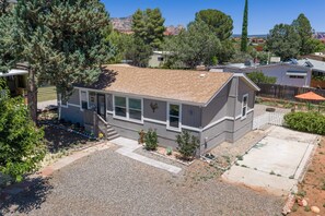 A single-story house with a tiled roof, a front porch, and a small front yard with a gravel driveway. - West Sedona Retreat - Near Trails & Red Rocks (Sedona)