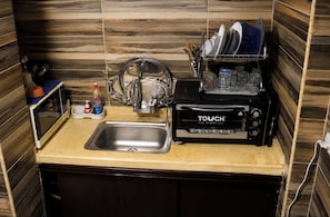 A compact kitchen with a sink, a dish drying rack, a toaster, and a dish soap bottle.