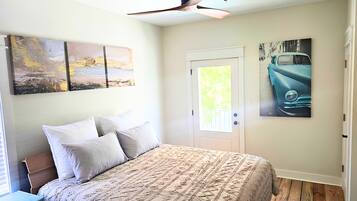 A bedroom with a bed, a ceiling fan, and artwork on the walls.