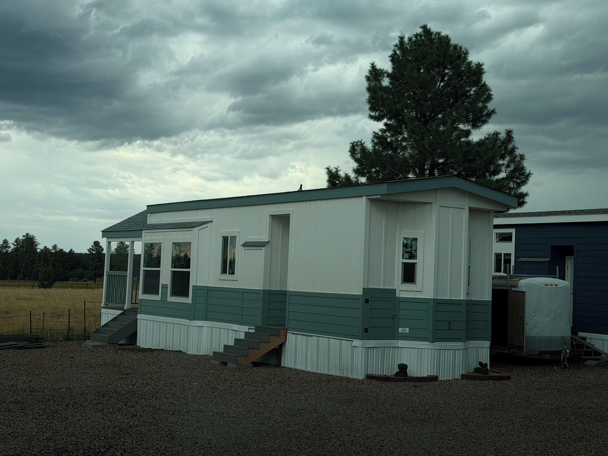 A single-story cabin with a front porch, a small staircase, and a fenced yard.