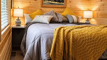 Ein gemütliches Schlafzimmer mit einem Bett, Kissen, einer Decke und einem Gemälde an der Wand.