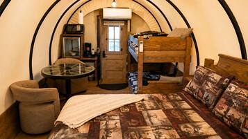 Une chambre compacte comprenant un lit superposé, une petite table avec une chaise, un four à micro-ondes et une machine à café.