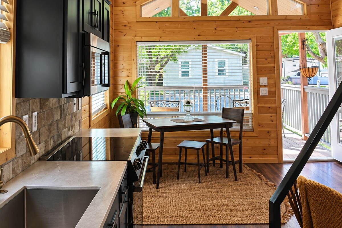A wooden interior with a kitchen, dining area, and a view to the outside.