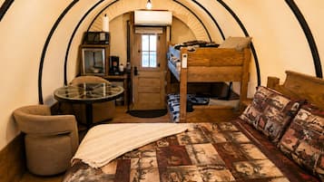 Habitación pequeña con una cama litera, una mesita con silla, microondas y cafetera.