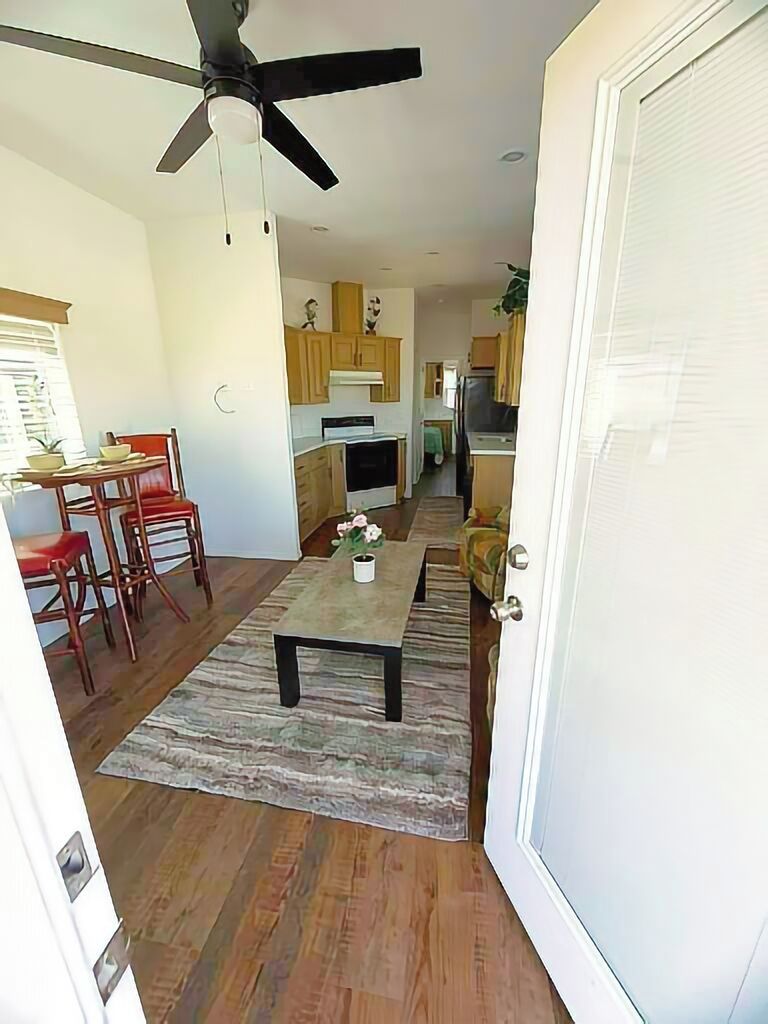 Une cuisine moderne avec des meubles en bois, un coin repas comprenant une table et des chaises, et un ventilateur de plafond.