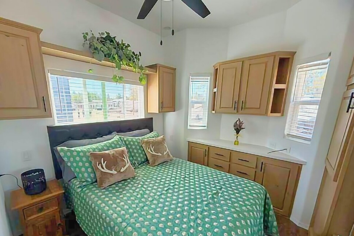 A bedroom with a bed, wooden cabinets, a window, and a ceiling fan.