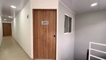 A hallway with a wooden door labeled '201' and a window on the adjacent wall.