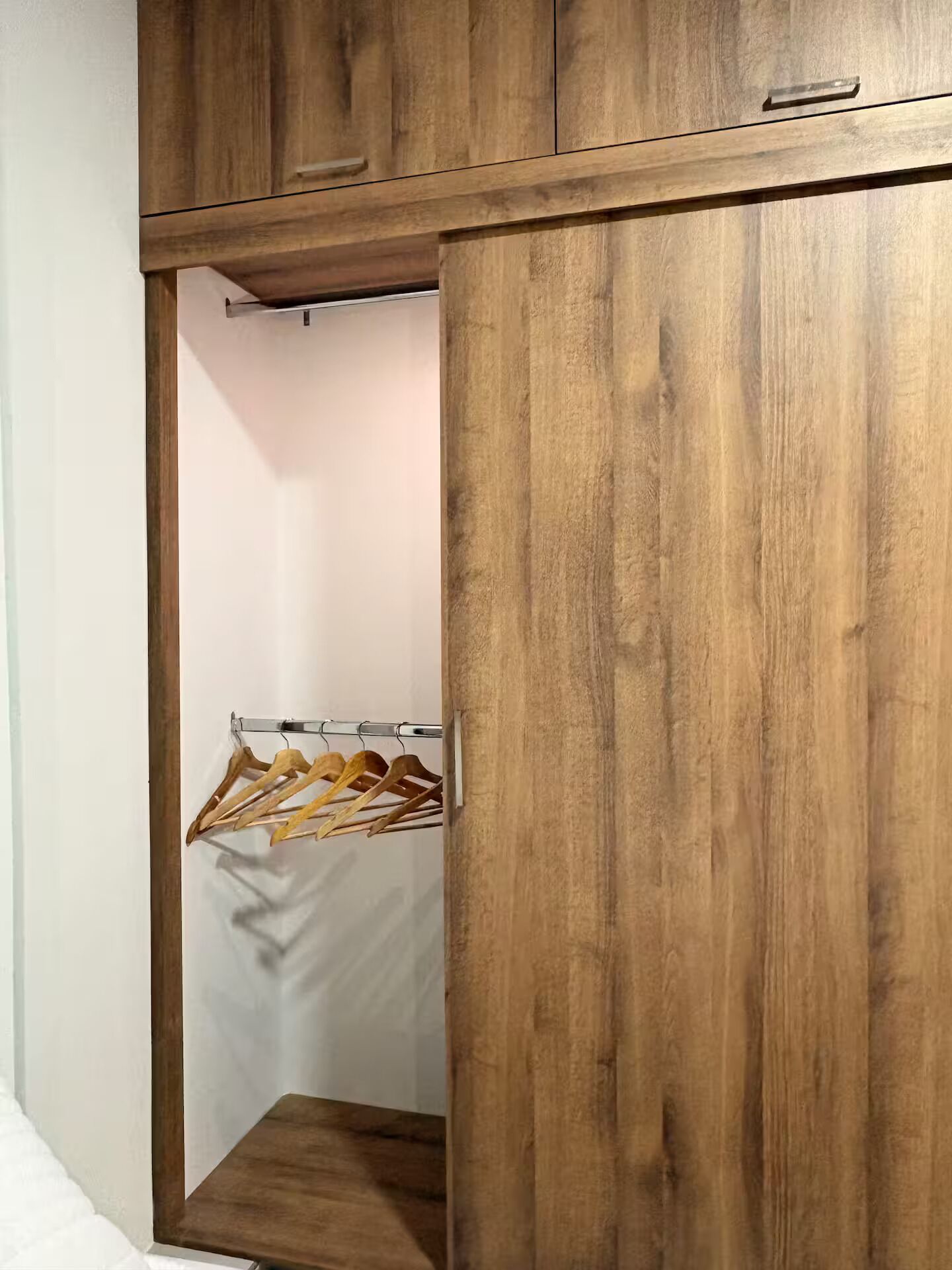A wooden wardrobe with a hanging rack inside.
