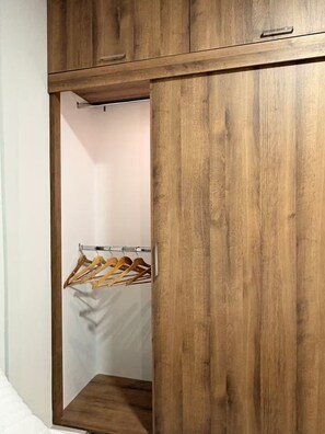 A wooden wardrobe with a hanging rack inside.
