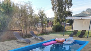 A swimming pool with a blue border, surrounded by a wooden deck.