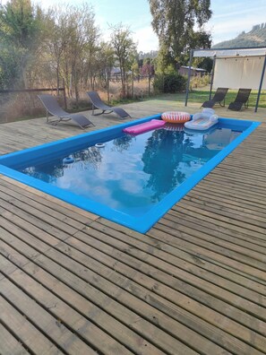 A swimming pool with a blue border, surrounded by a wooden deck.