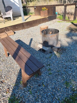 A wooden bench and a metal fire pit on a gravel surface. - Rincón de Colbún Cabin (Colbun)