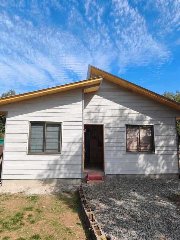 A single-story house with a gabled roof, a front door, and two windows.