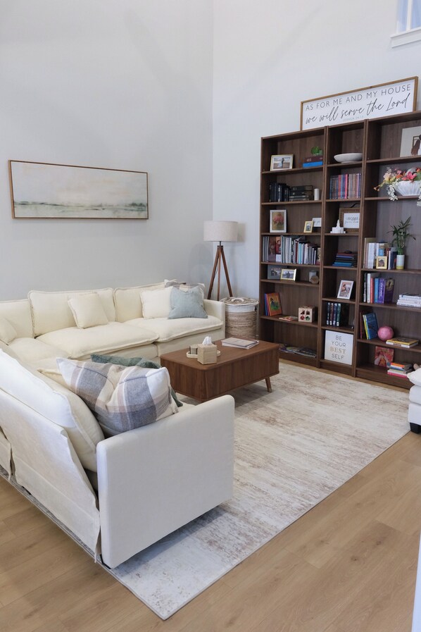Una sala de estar con un sofá, una mesa de centro y una estantería llena de libros y objetos decorativos.