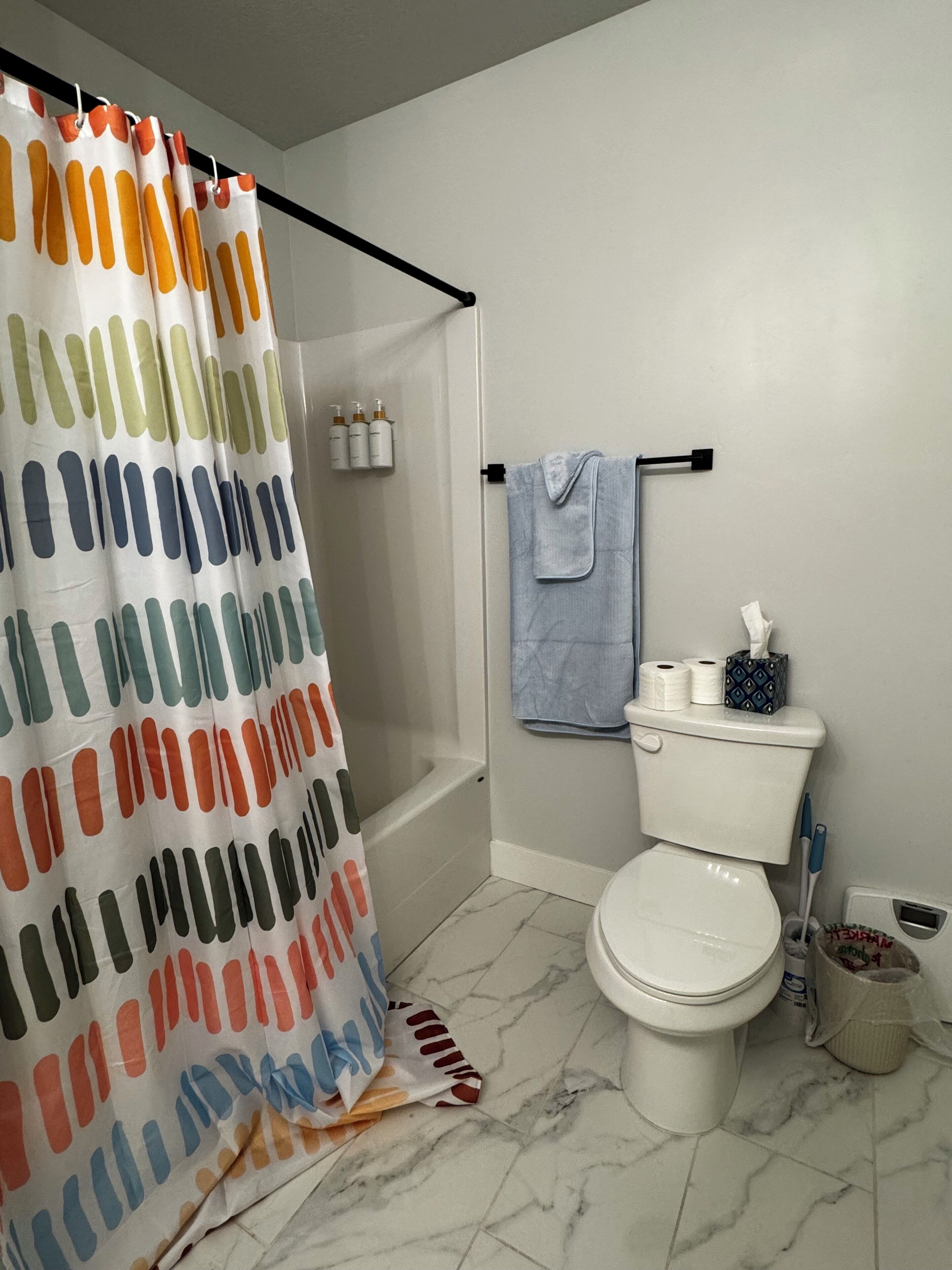Un baño con cortina de ducha, inodoro y barra para toallas.
