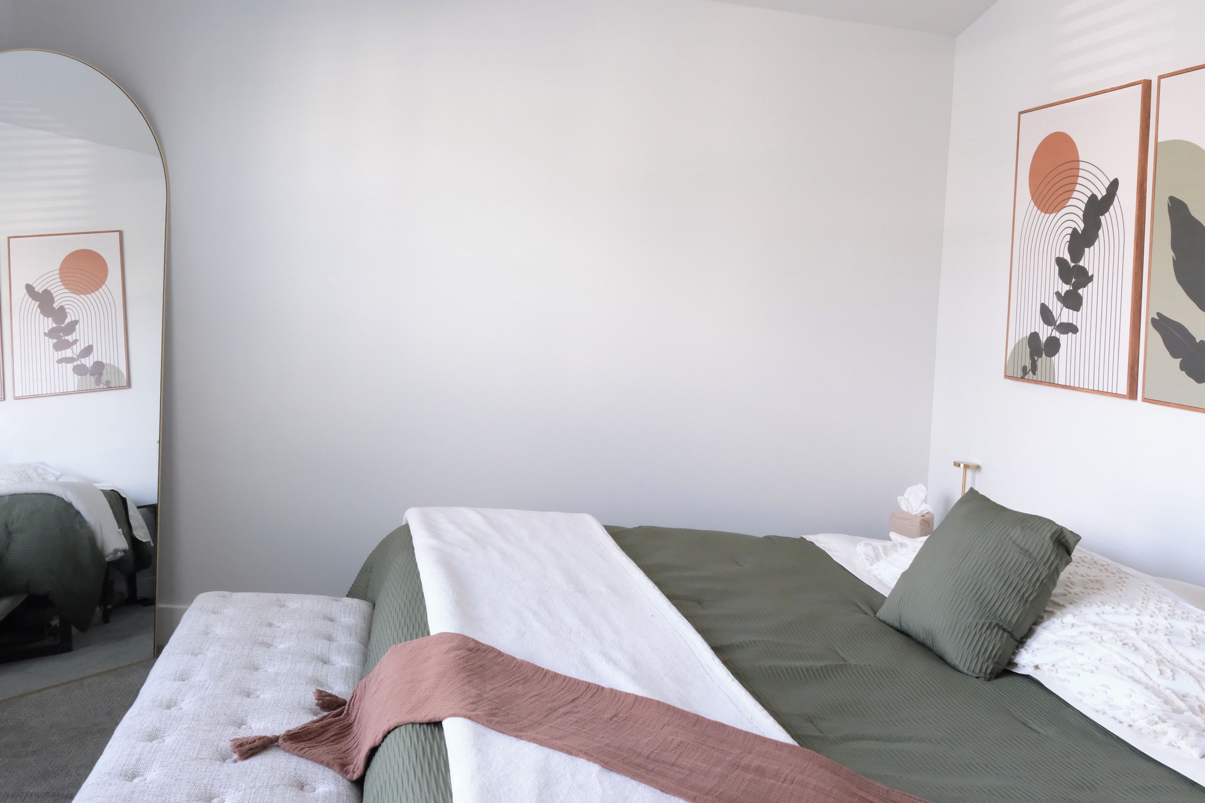Quarto com uma cama, mesa de cabeceira e parede decorada com obras de arte.