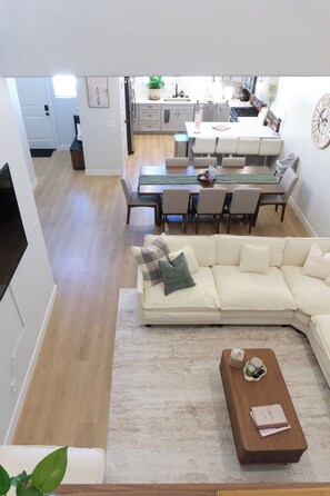 A modern living room with a sectional sofa, a coffee table, and a dining area with chairs and a table.