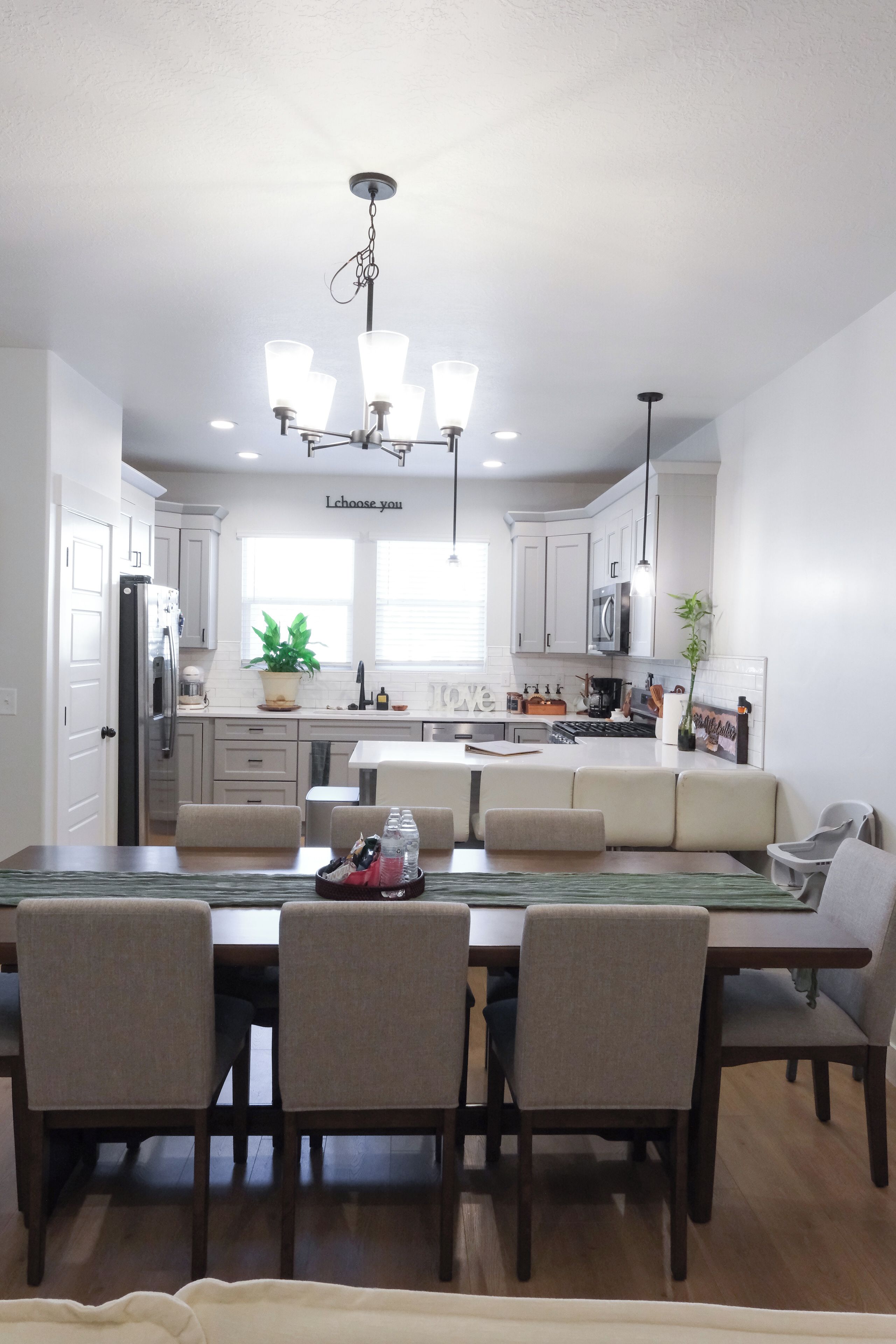 A modern kitchen with white cabinets, a central island, and a dining area with four chairs.