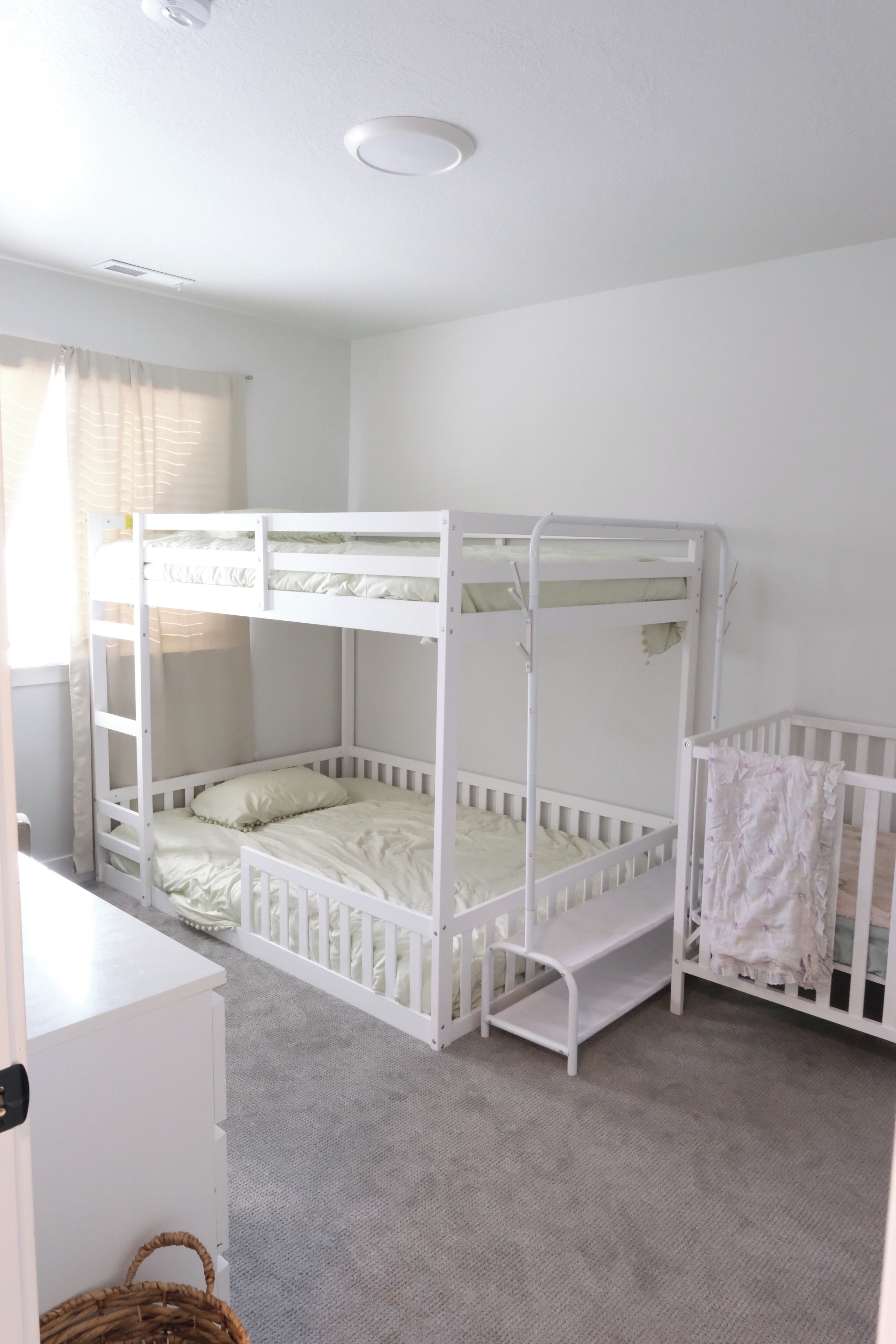 Une chambre avec un lit superposé, un berceau étant fixé sur le côté droit.