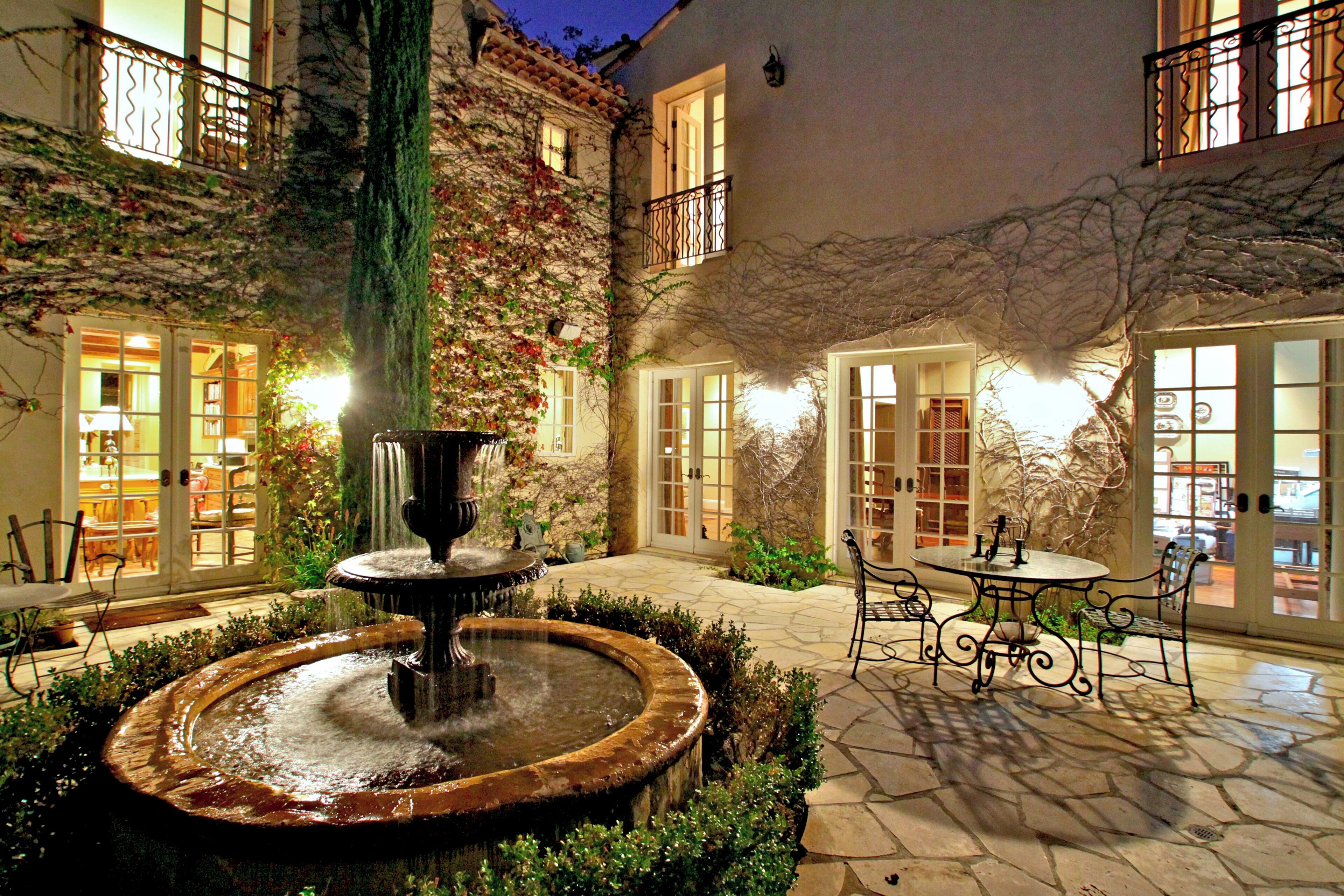 Un patio con una fuente, asientos al aire libre y un edificio con múltiples ventanas y balcones.