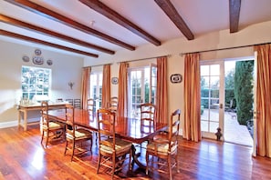 A dining room with a wooden table and chairs, large windows, and a view of the outdoors. - Phenomenal Private Estate with pool and spa in San Juan Capistrano.4-bed, 6 bath (San Juan Capistrano)