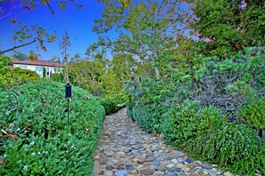 A stone pathway leading through a garden with various plants and shrubs. - Phenomenal Private Estate with pool and spa in San Juan Capistrano.4-bed, 6 bath (San Juan Capistrano)