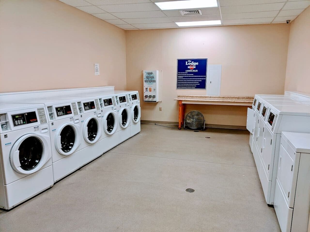 A laundry facility with multiple washing machines, a dryer, and a sign indicating the location.