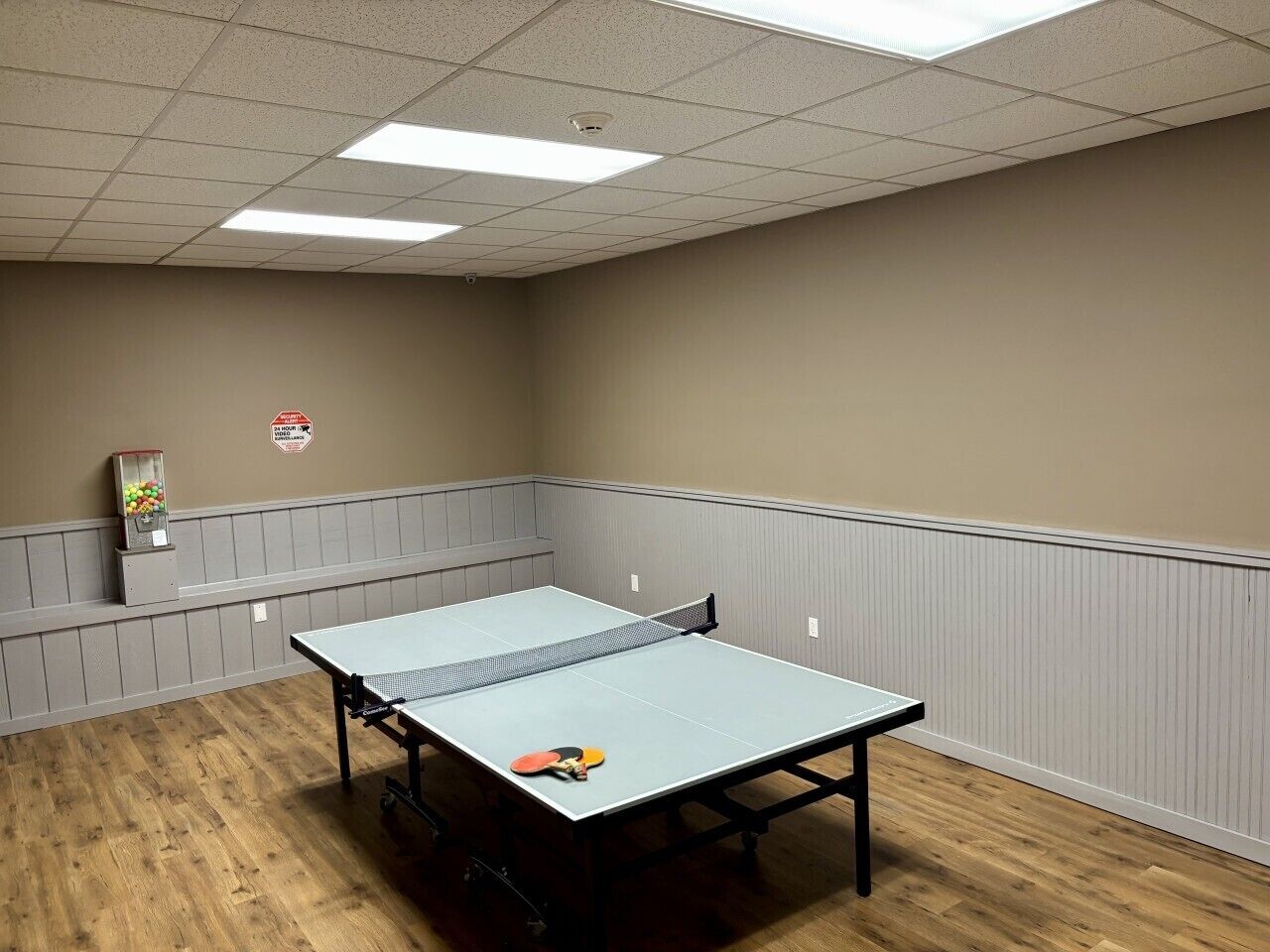 Ein Tischtennis-Tisch in einem Raum mit Holzboden und weißer Decke.