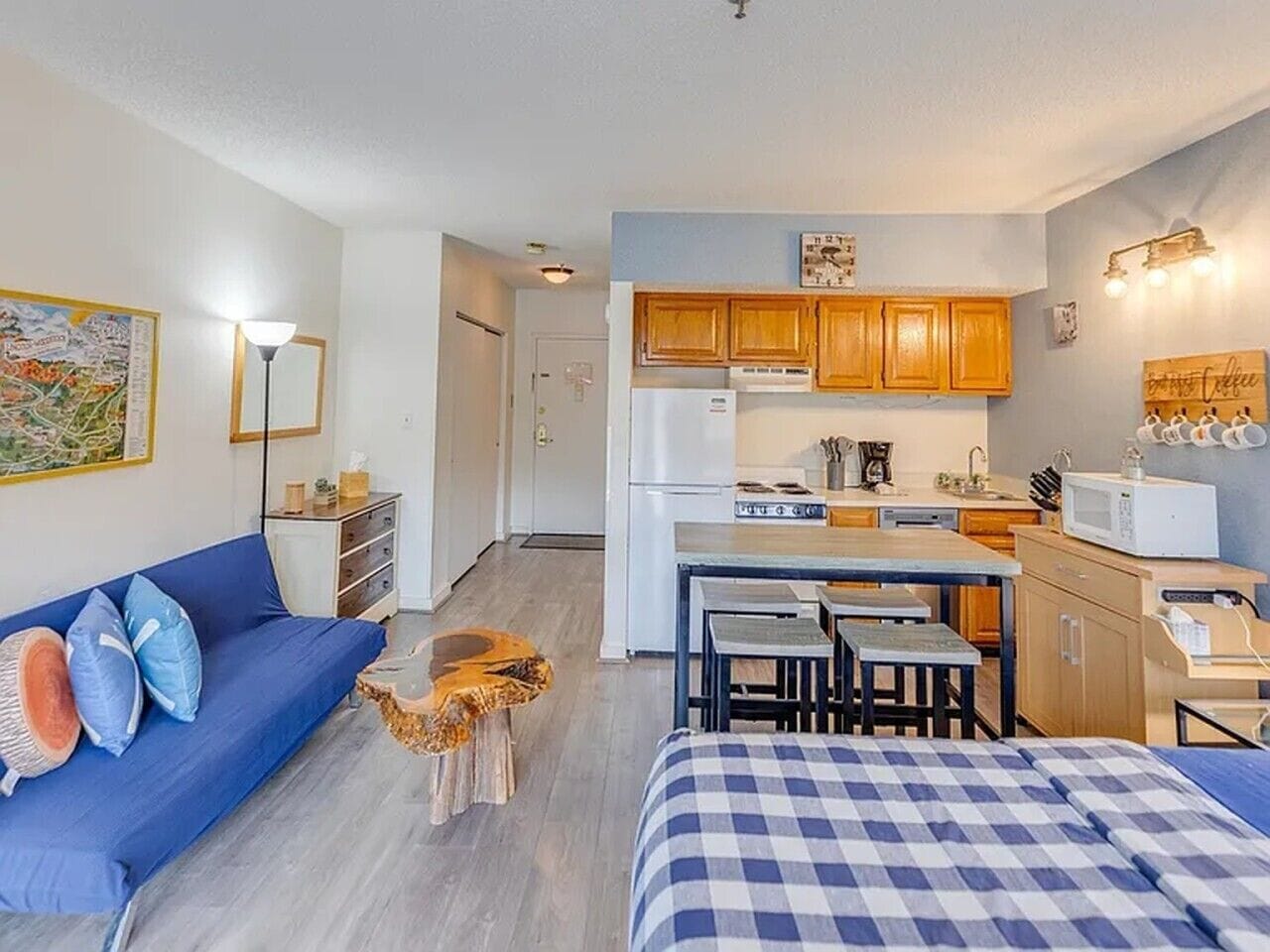 Un espacio habitable compacto con kitchenette, un sofá, zona de comedor y cama.