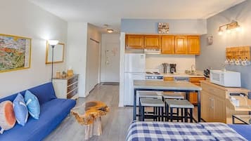 Un espacio habitable compacto con kitchenette, un sofá, zona de comedor y cama.