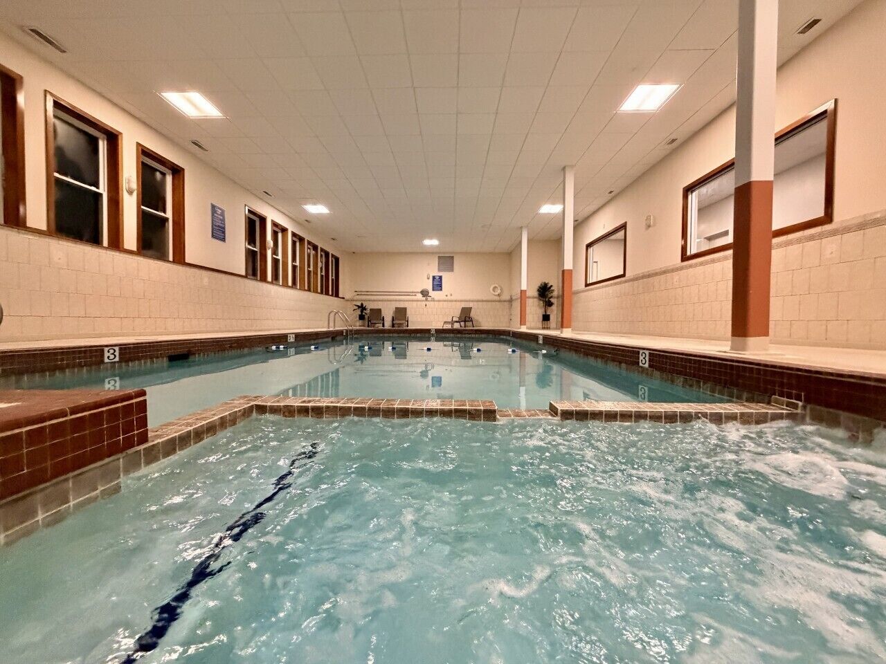 Una piscina interior con agua cristalina, paredes y piso de azulejos.