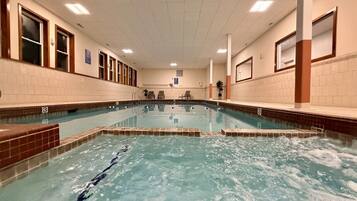 Una piscina interior con agua cristalina, paredes y piso de azulejos.